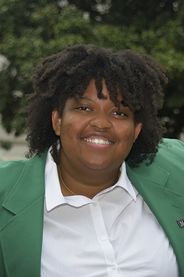 Close up headshot of a young woman wearing a green blazer.