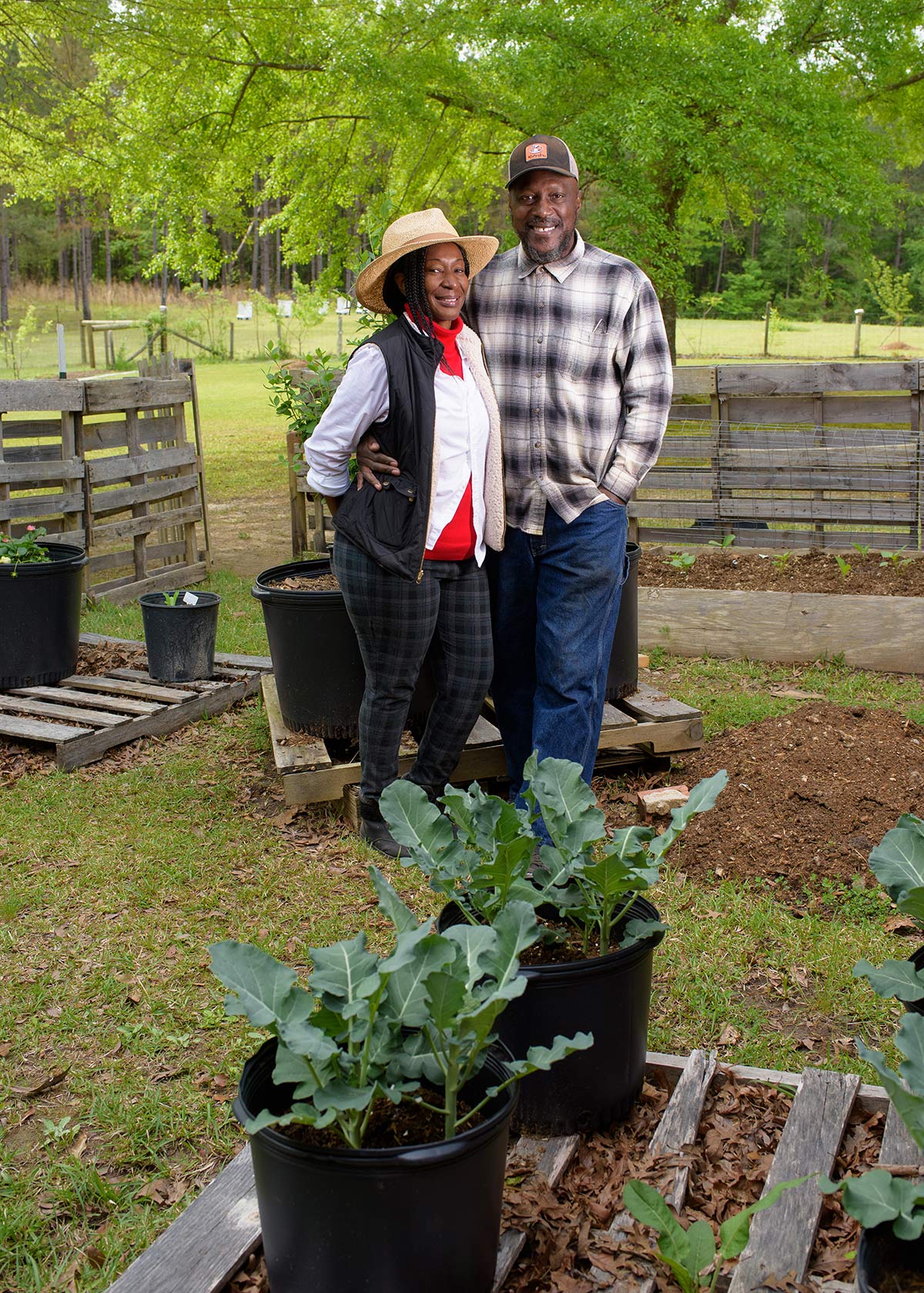 A smiling couple standing next to each other in a garden.