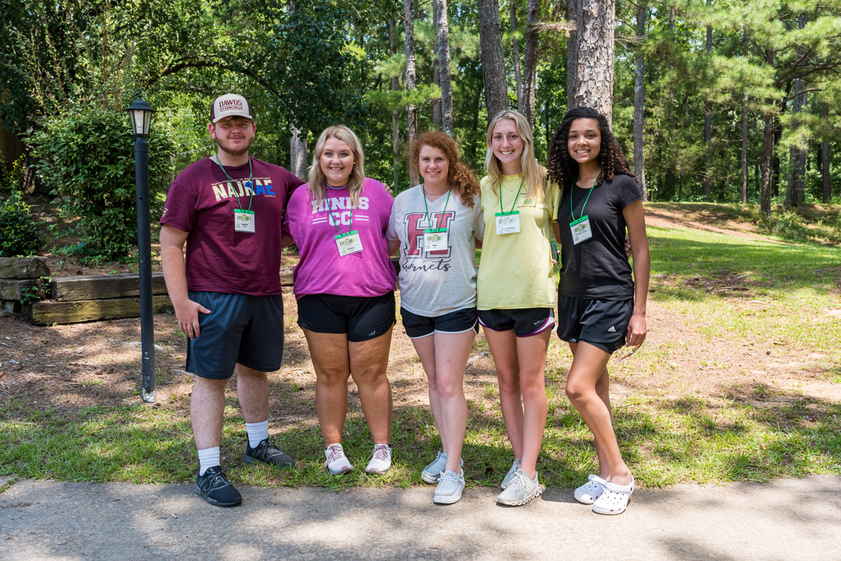 A young man and four young women pose for a group photo.