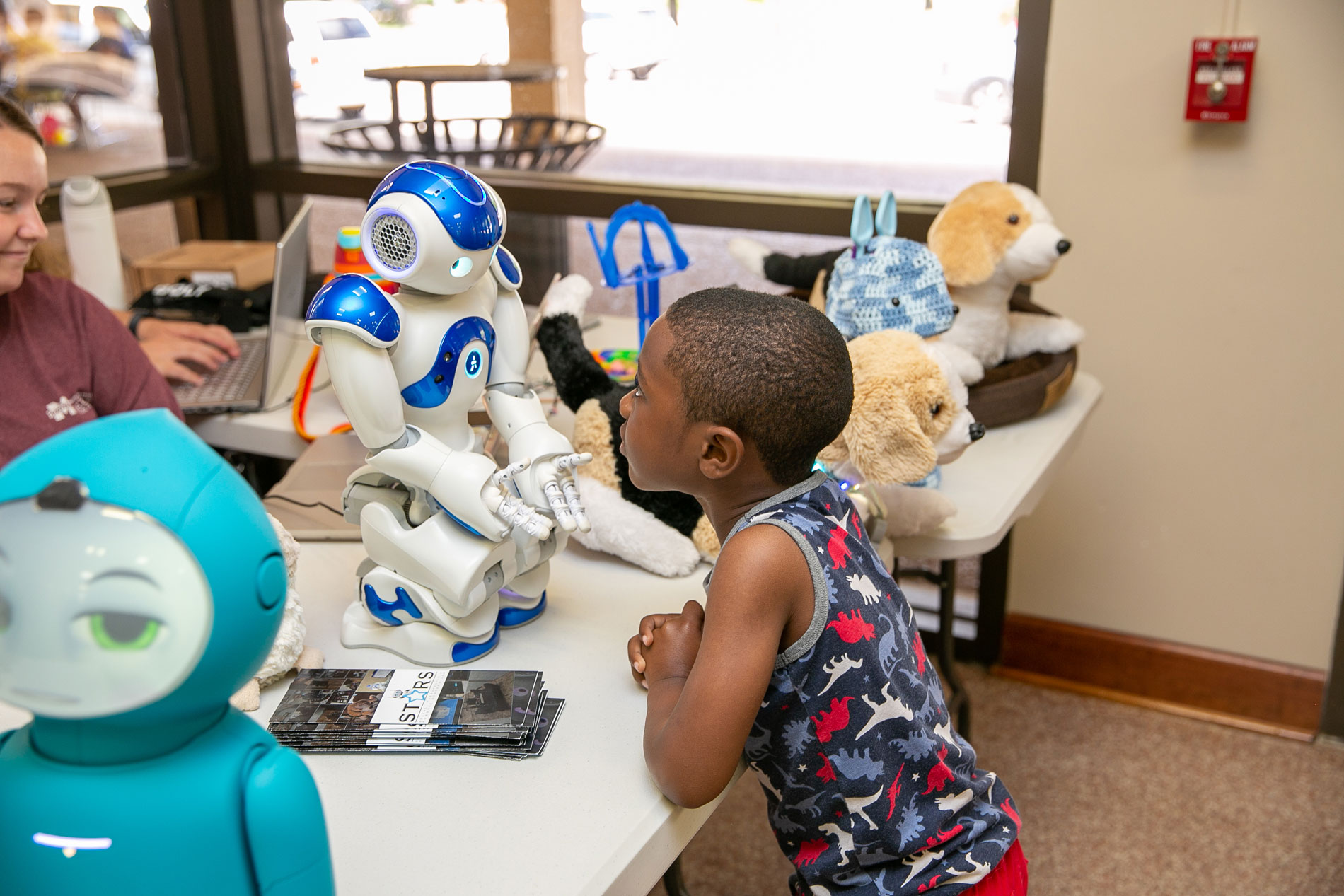 A boy looking intently at a robot.