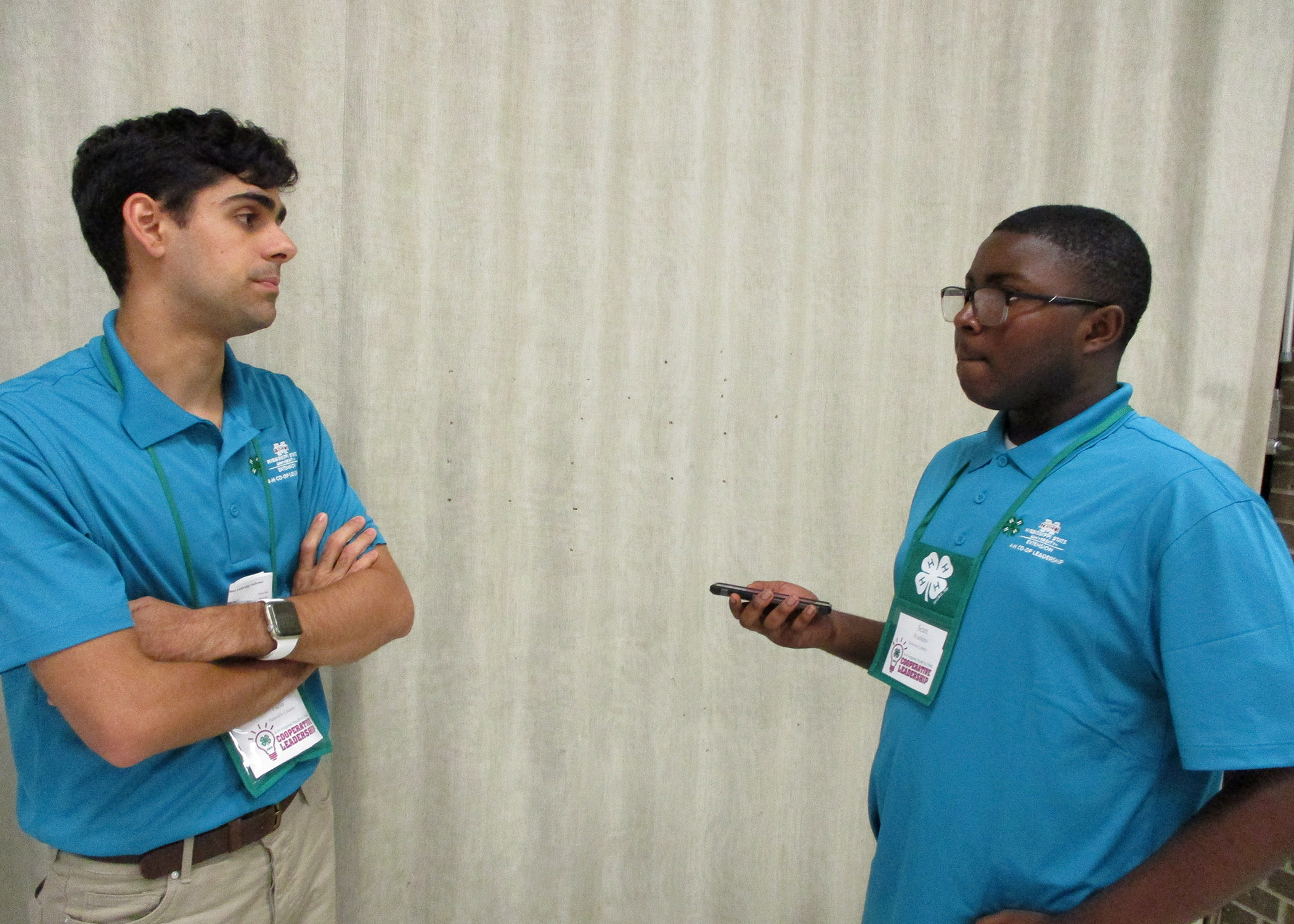 Two young men wearing blue shirts talking to each other