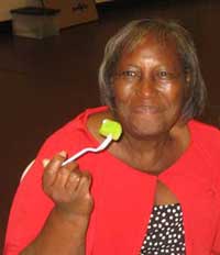 Woman in a red sweater and black polka-dotted shirt smiles as she eats.