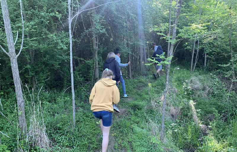 People walking a small trail in the forest.