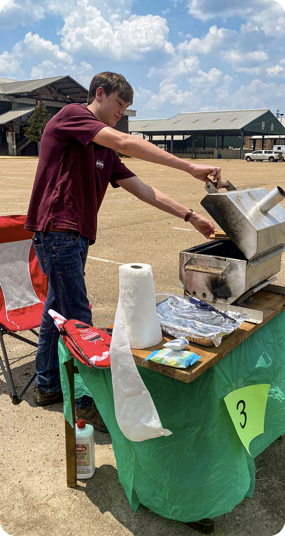 A contestant is cooking over a hot grill on a small table.