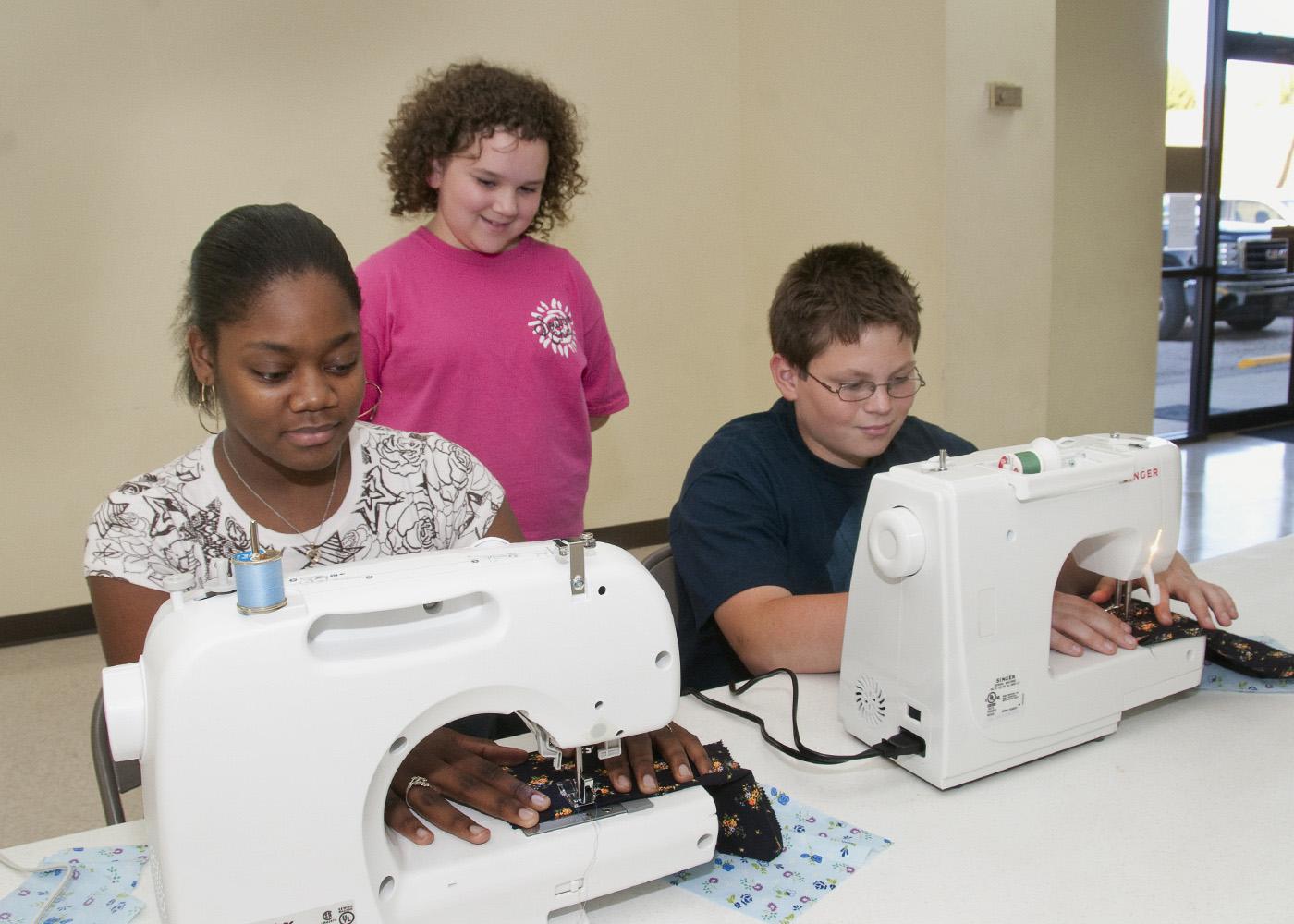 Calhoun County youth have an opportunity to learn the art of sewing through a new 4-H club named "A Stitch in Time." Operating the new computerized sewing machines donated by Singer Co. and "Heirlooms Forever" of Tupelo are, from left, Keyonia McGuirt of Pittsboro and Taylor Liles of Calhoun City. Observing is Hannah Long of Calhoun City. (Photo by Scott Corey)