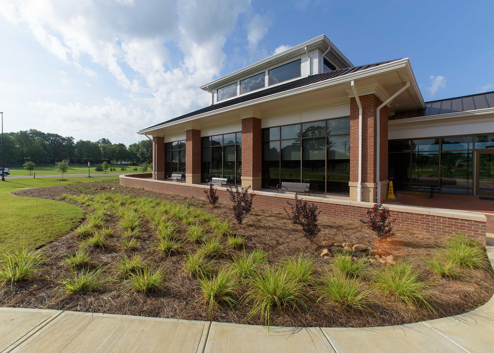 Grasses and small bushes adorn a landscape bed in front of a building.