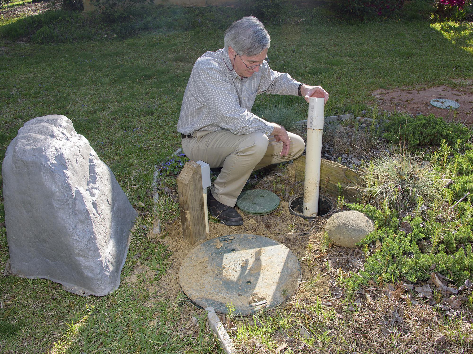 Gray water can be used for lawn and garden irrigation, which is how Mike Boyles, a homeowner in Winston County, uses his recycling system. Here, Boyles is inspecting the access point he uses for water treatment. (Photo by MSU Extension Service/Kevin Hudson)