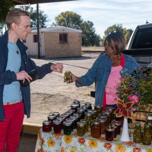 A woman giving a man a jar of food.