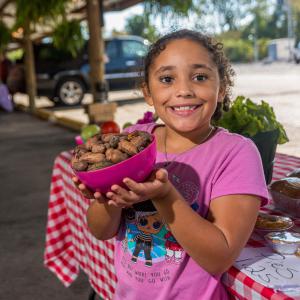 A girl holding a bowl of pecans.