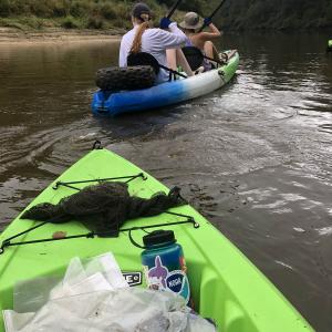 View from a green kayak of the back of two women paddling a kayak. 