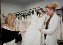 Jennifer Burt, left, and Christine Barker, of Christine's Couture in Starkville, examine the intricate patterns of beading and lace that commonly adorn authentic designer wedding gowns. Handsewn embellishments like these are never seen on counterfeit dresses. (Photo by Scott Corey)