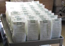 White bags stand in four rows on a gray cart.