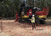 A man wearing a hard hat talking into a microphone in front of a piece of heavy equipment.