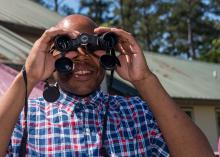 A man holds a pair of binoculars to his face. 