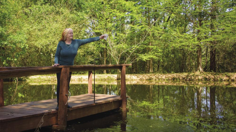 Woman standing on pier in lake holding cup of water