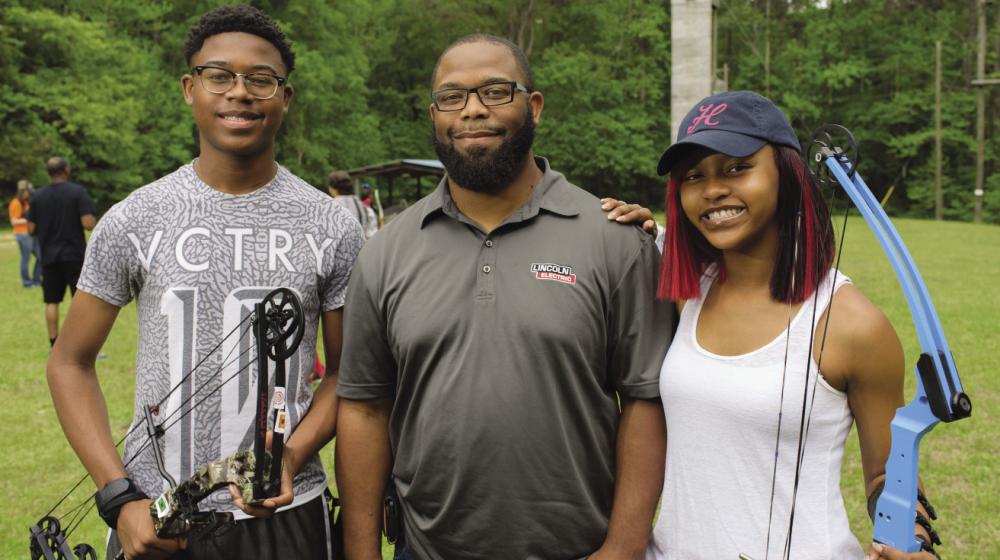 A 4-H volunteer leader with two 4-H members at a 4-H Shooting Sports event.