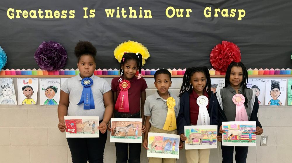 Students holding their award winning drawing of horse from a story