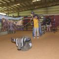 A young boy throws a rope toward a fake bull with the help of an older man standing behind him.