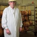 A man stands in front of a rack holding meat.