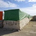 Picked cotton sits in large green and red bales.