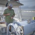 A man stands on a boat and checks a large roll of fishing line.