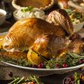 A roasted turkey and side dishes fill a table set for a meal.