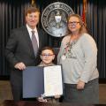 Three individuals pose with a newly signed proclamation.