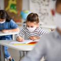 Three students wear face masks as they sit at their desks.