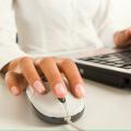 A person’s right hand rests on a computer mouse while their left hand rests on a laptop keyboard.