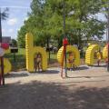 Children stand and sit around life-size, bright-yellow letters that spell out “share.”